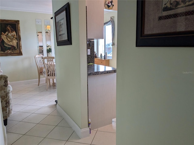 corridor featuring ornamental molding and light tile patterned flooring