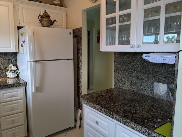 kitchen with white fridge, white cabinetry, light tile patterned floors, and decorative backsplash