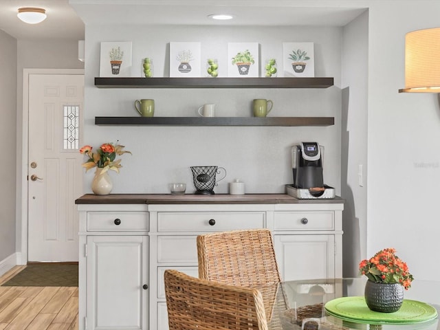 bar featuring light wood-type flooring and white cabinets