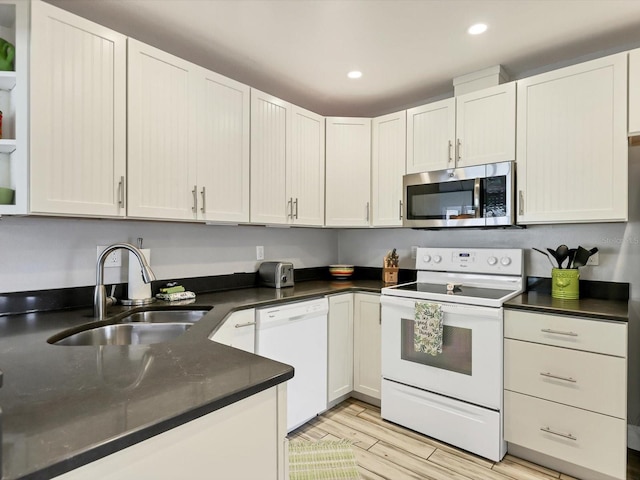 kitchen with white appliances, white cabinetry, sink, and light wood-type flooring