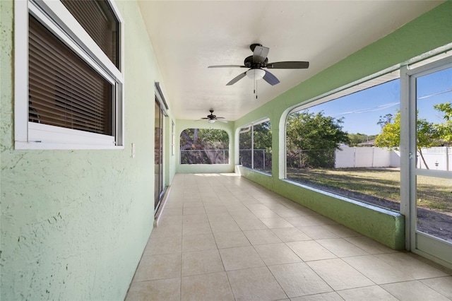 unfurnished sunroom with ceiling fan