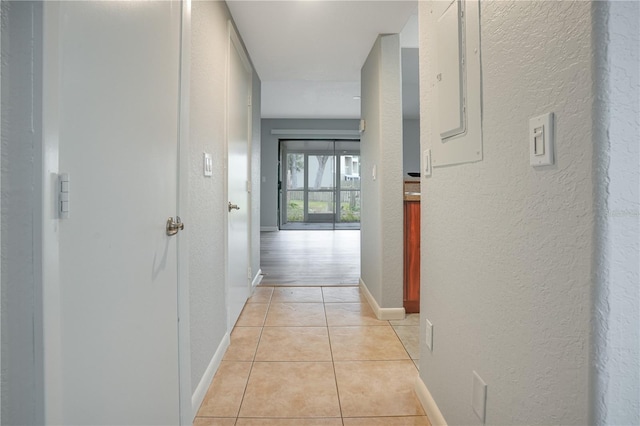 corridor featuring electric panel and light tile patterned floors