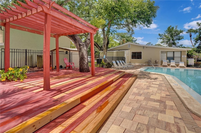 view of swimming pool with a patio area, a wooden deck, and a pergola