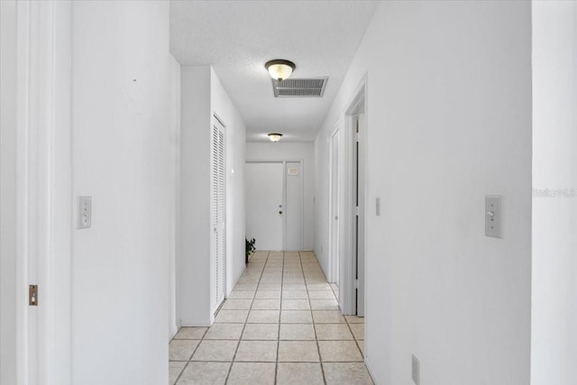 corridor featuring a textured ceiling and light tile patterned flooring