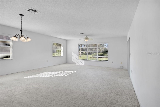 carpeted spare room with a textured ceiling, plenty of natural light, and ceiling fan