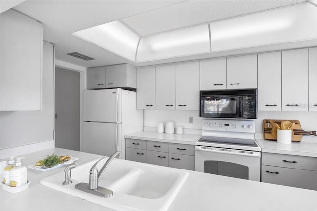 kitchen with white appliances, white cabinetry, and sink