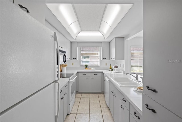 kitchen with sink, white cabinets, white appliances, and light tile patterned flooring