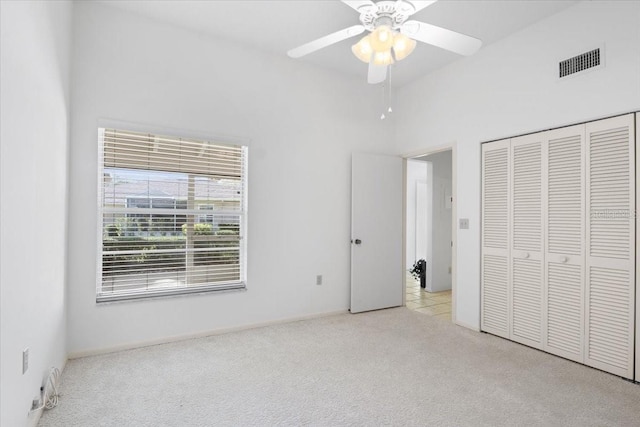 unfurnished bedroom with light colored carpet, a closet, and ceiling fan