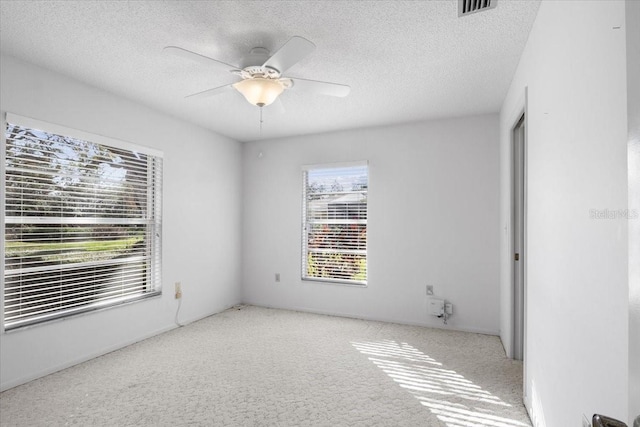 spare room featuring light carpet, a textured ceiling, and ceiling fan