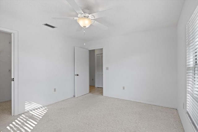 unfurnished bedroom featuring ceiling fan, light carpet, and a textured ceiling