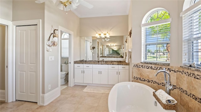 bathroom featuring vanity, tile patterned flooring, a bathing tub, toilet, and ceiling fan