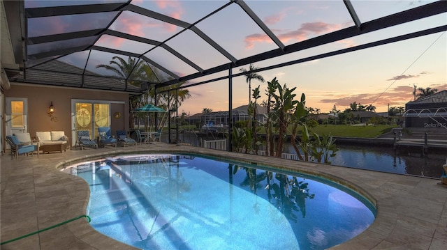 pool at dusk featuring a patio and glass enclosure