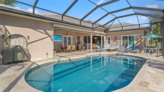 view of pool with grilling area, glass enclosure, a patio, and ceiling fan