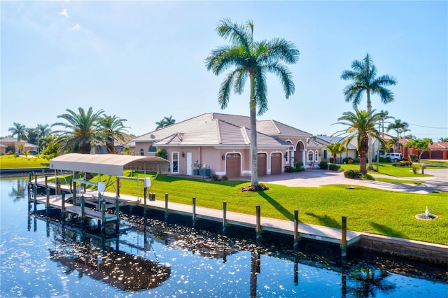 rear view of house featuring a garage, a yard, and a water view