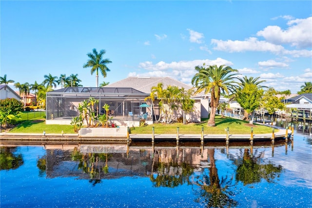 back of property with a lanai, a water view, and a lawn