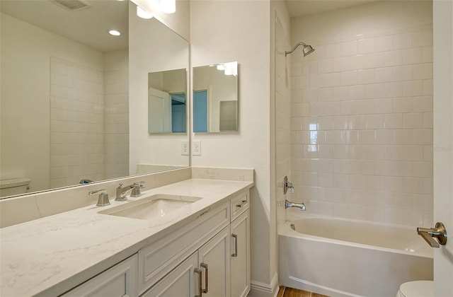 full bathroom with vanity, tiled shower / bath combo, and toilet