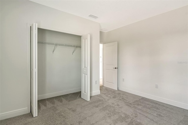 unfurnished bedroom with light carpet and a closet