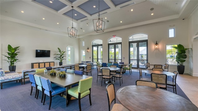 dining room featuring coffered ceiling, a chandelier, a towering ceiling, and french doors