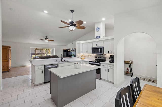 kitchen with kitchen peninsula, ceiling fan, appliances with stainless steel finishes, white cabinetry, and sink