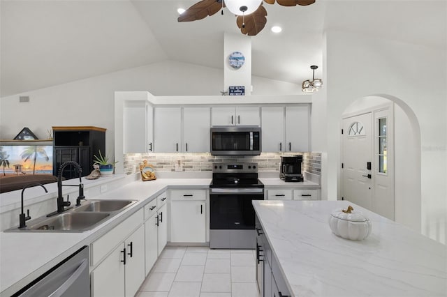 kitchen featuring lofted ceiling, stainless steel appliances, sink, white cabinets, and tasteful backsplash