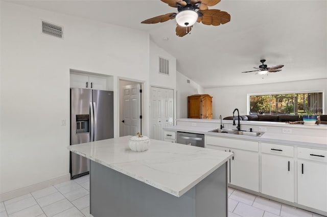 kitchen with appliances with stainless steel finishes, sink, a kitchen island, kitchen peninsula, and white cabinetry