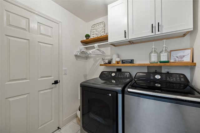 washroom featuring washer and dryer, a textured ceiling, cabinets, and light tile patterned floors