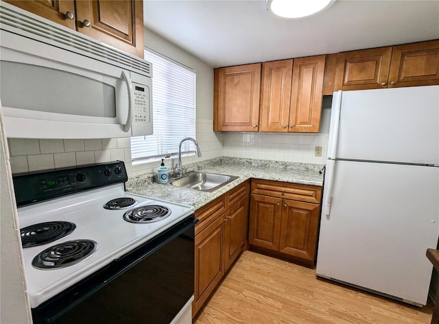 kitchen featuring light stone countertops, sink, tasteful backsplash, light hardwood / wood-style floors, and white appliances