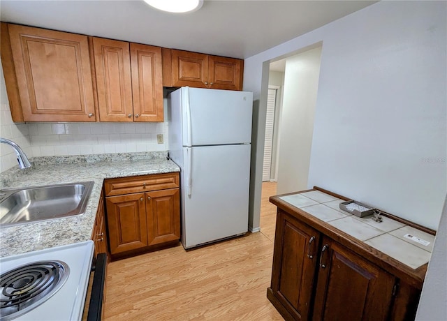 kitchen with white appliances, backsplash, light hardwood / wood-style flooring, and sink