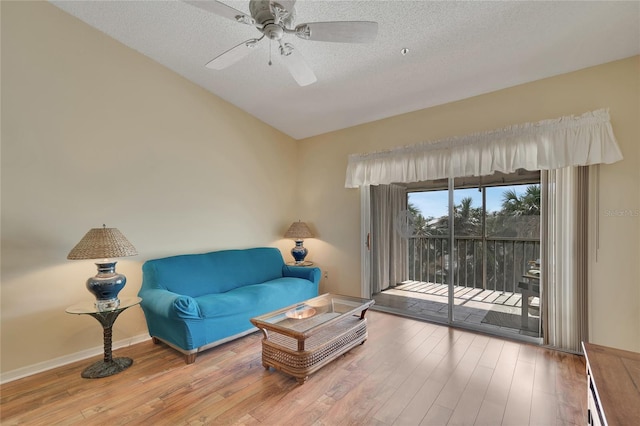 living area with a textured ceiling, hardwood / wood-style flooring, and ceiling fan