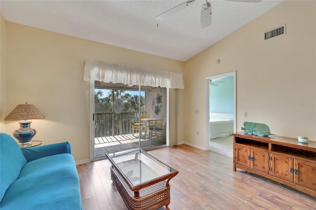 living room featuring ceiling fan, light wood-type flooring, a textured ceiling, and high vaulted ceiling