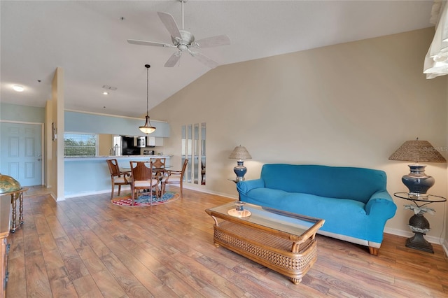 living room featuring ceiling fan, vaulted ceiling, and light wood-type flooring