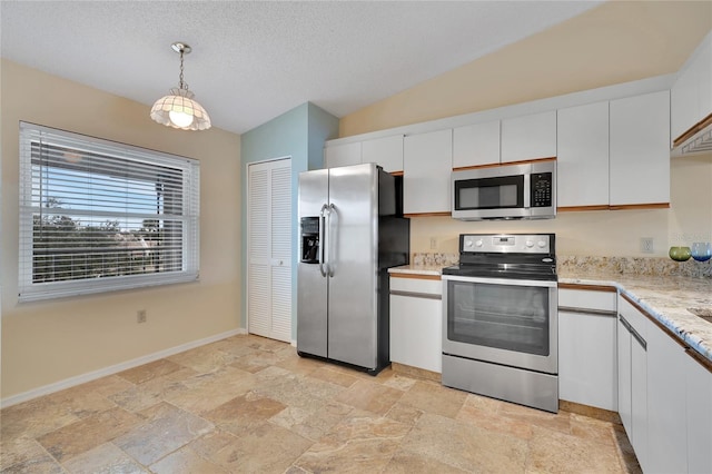 kitchen with lofted ceiling, white cabinets, decorative light fixtures, and appliances with stainless steel finishes