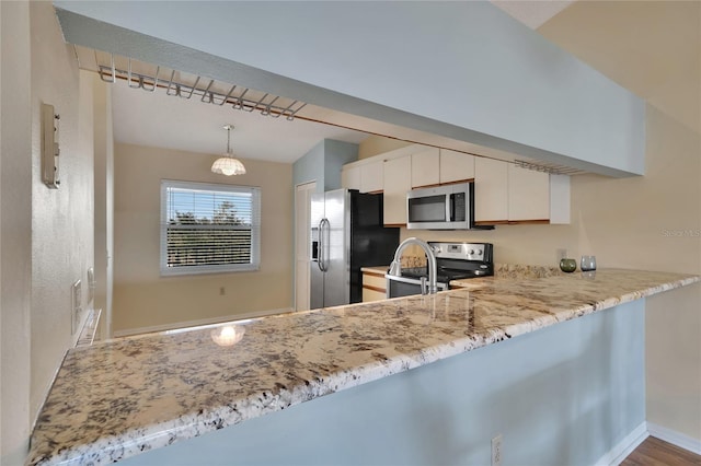 kitchen with kitchen peninsula, appliances with stainless steel finishes, decorative light fixtures, white cabinets, and hardwood / wood-style flooring