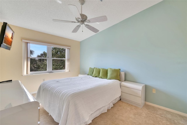 bedroom with ceiling fan, light colored carpet, and a textured ceiling