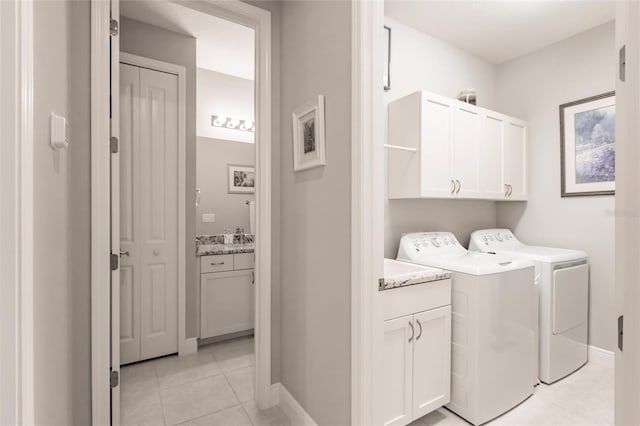 laundry room with cabinets, light tile patterned flooring, and washing machine and dryer