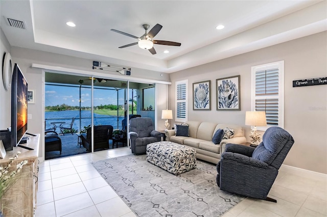 living room featuring light tile patterned floors, a raised ceiling, and ceiling fan