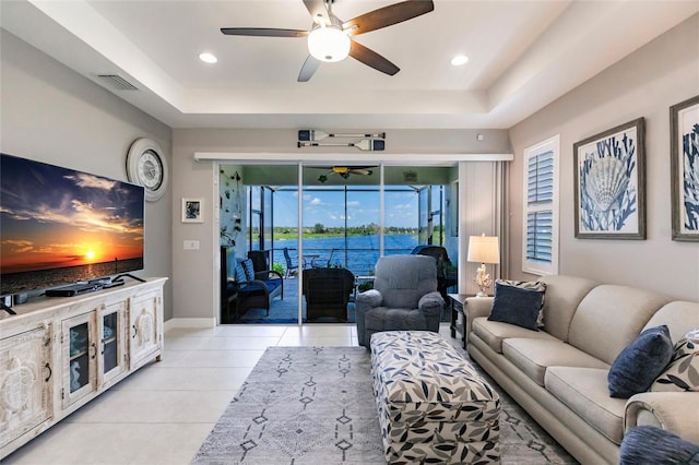 living room with light tile patterned floors, a raised ceiling, and ceiling fan