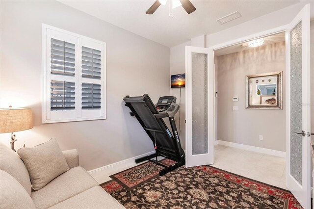 exercise room featuring french doors, light tile patterned floors, and ceiling fan