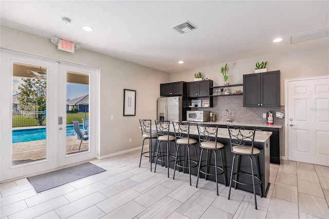 kitchen featuring a kitchen bar, stainless steel fridge, a center island, and french doors