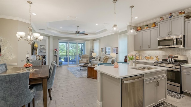 kitchen with pendant lighting, a center island with sink, stainless steel appliances, and ceiling fan with notable chandelier