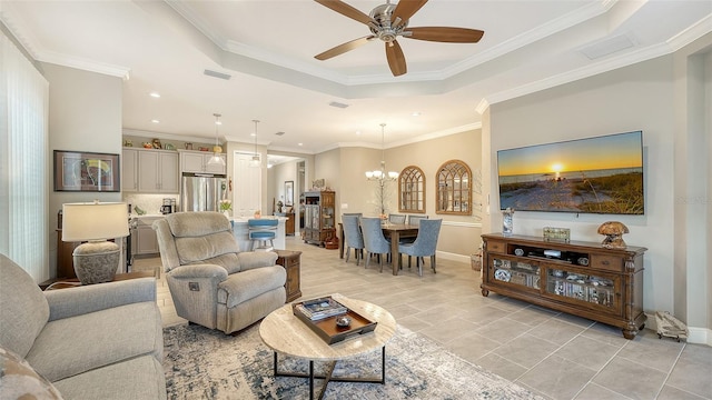 living room featuring light tile patterned floors, ceiling fan with notable chandelier, a raised ceiling, and ornamental molding