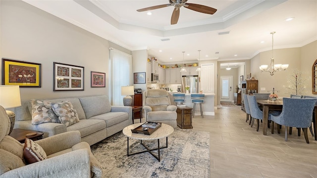 living room featuring ceiling fan with notable chandelier, crown molding, and a tray ceiling