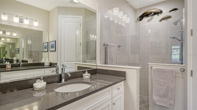 bathroom featuring tiled shower and vanity