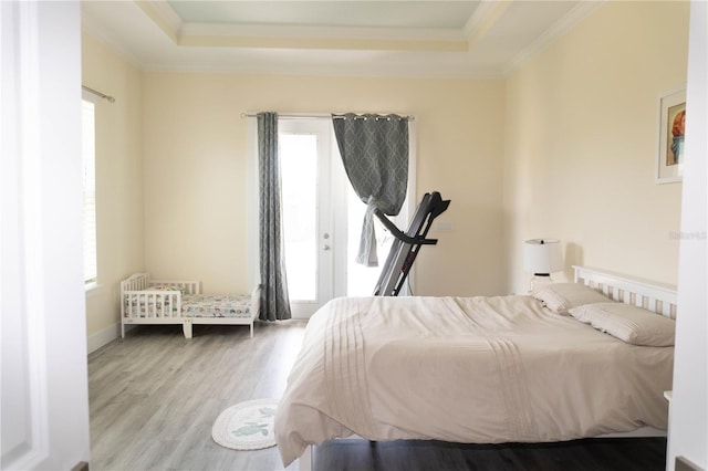 bedroom with a raised ceiling, ornamental molding, and light hardwood / wood-style flooring