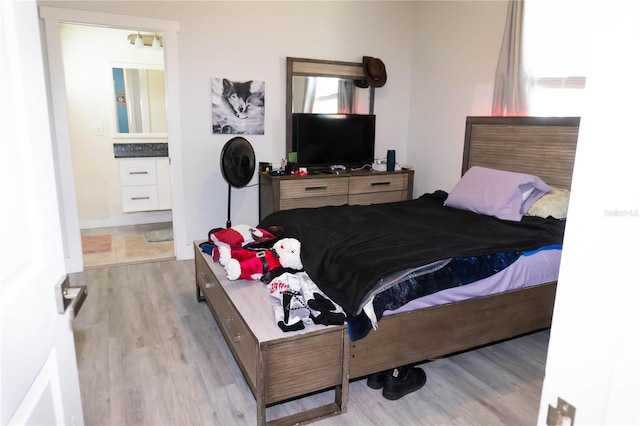 bedroom featuring ensuite bathroom, multiple windows, and light wood-type flooring