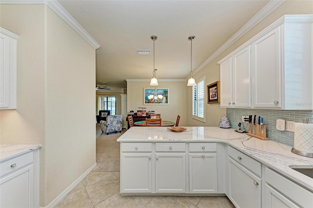 kitchen with ornamental molding, kitchen peninsula, white cabinetry, and a healthy amount of sunlight