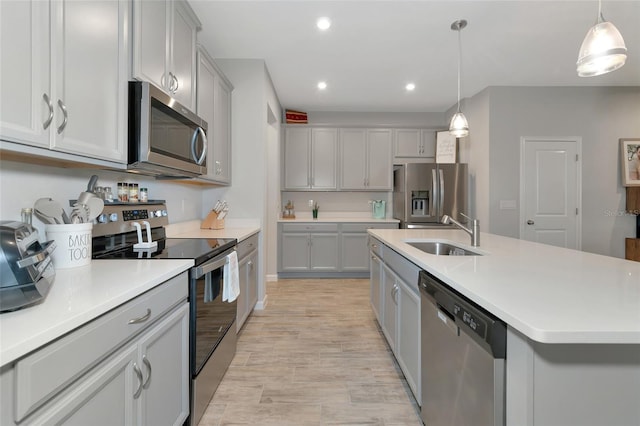 kitchen featuring sink, an island with sink, decorative light fixtures, and stainless steel appliances