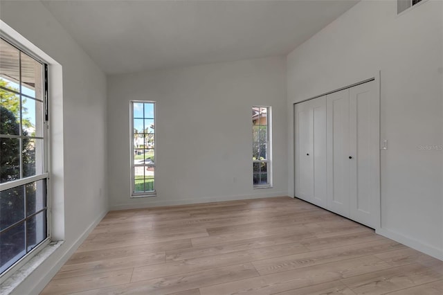 unfurnished bedroom featuring light hardwood / wood-style floors, vaulted ceiling, and multiple windows