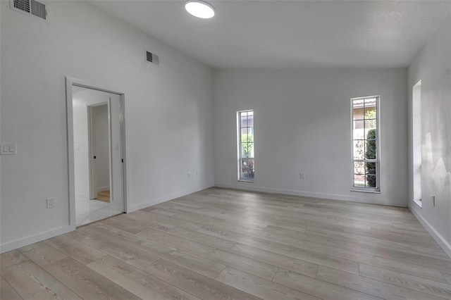 spare room featuring light wood-type flooring, vaulted ceiling, and plenty of natural light