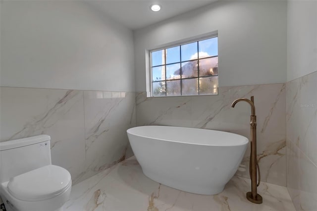 2303 89th St NW, Bradenton, FL 34209 - bathroom with tile walls, marble tiled floors, a freestanding bath, and wainscoting